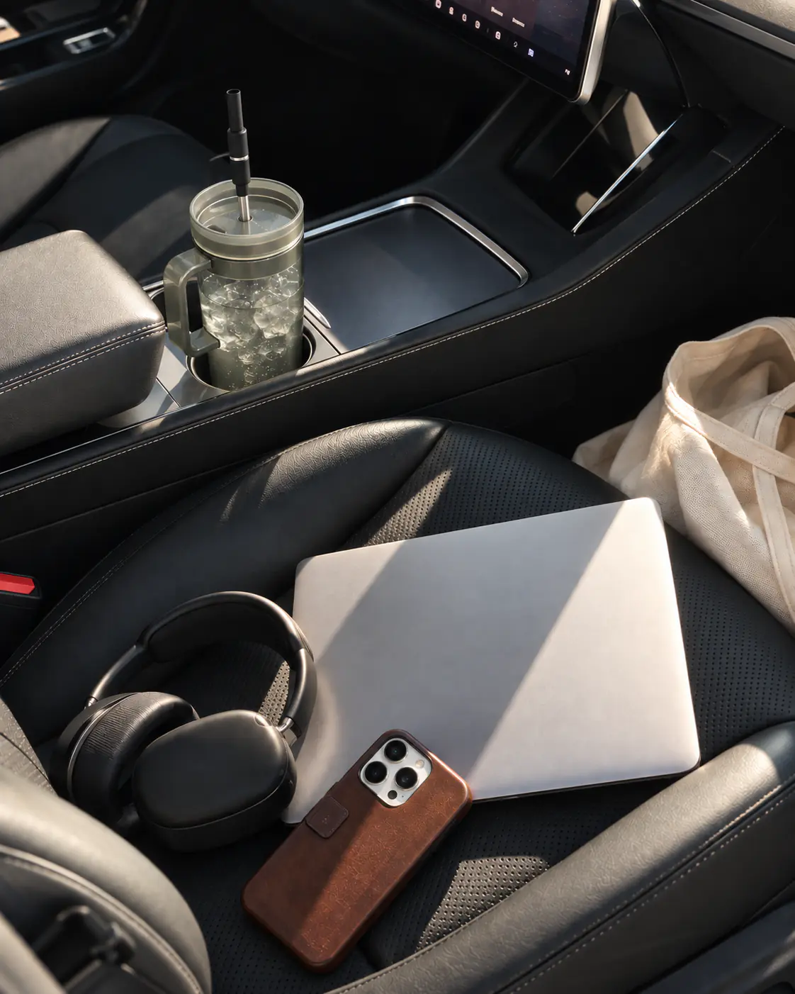 A clear tumbler with a black Aelo Straw in a car center console.