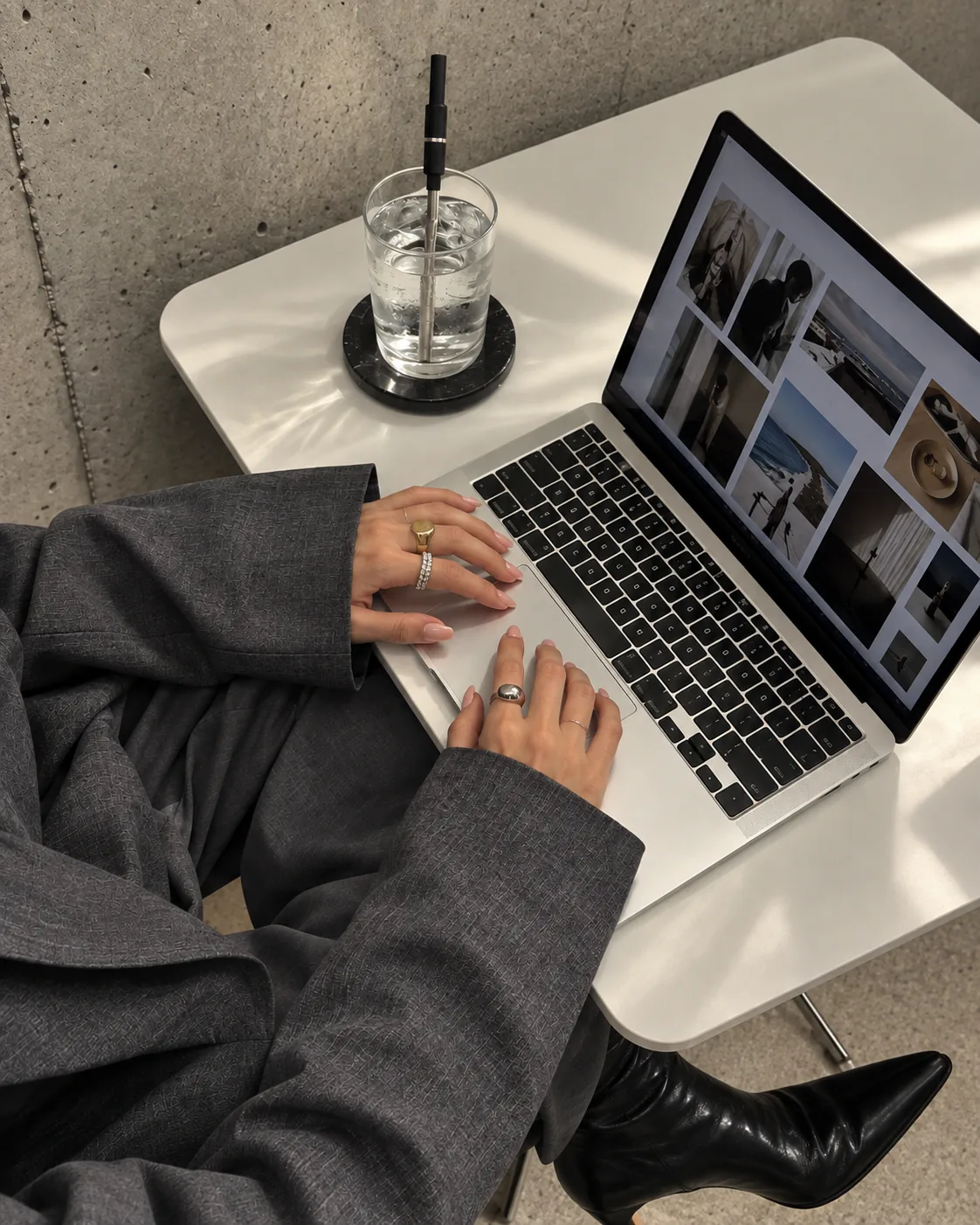 A glass with a black Aelo Straw on a desk beside a laptop.